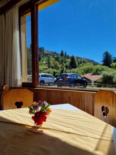 a table with a vase of flowers on top of it at Hotel La Cumbrecita in La Cumbrecita