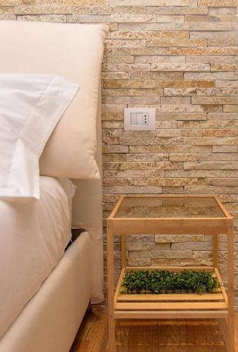 a bed with a table next to a brick wall at Aminta - Rooms & Wellness in Andria