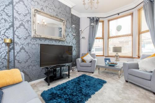 a living room with a television and a couch and chairs at SO-LUX in Belfast