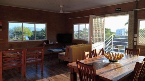 uma sala de jantar com mesa, cadeiras e janelas em Cobertura na Enseada a 80 m da areia em Ubatuba