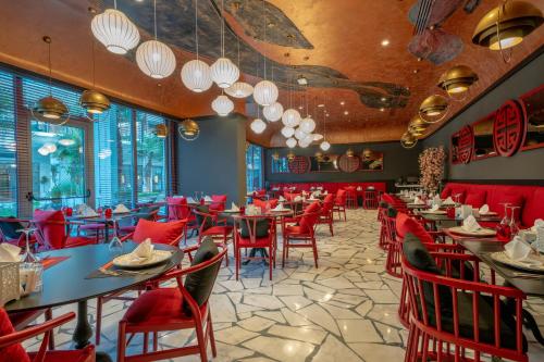 a restaurant with red chairs and tables and windows at Liberty Fabay - Ultra All Inclusive in Fethiye