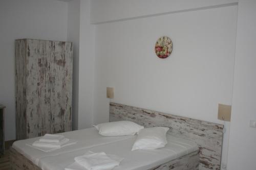 a white bed with white pillows and a clock on the wall at Hotel Mihaela in Mamaia