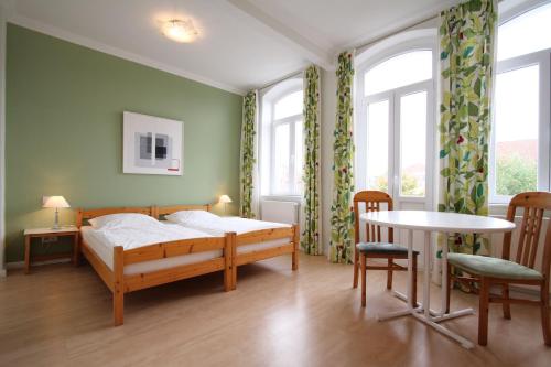 Schlafzimmer mit einem Bett, einem Tisch und Fenstern in der Unterkunft Hotel Galerie in Seelze