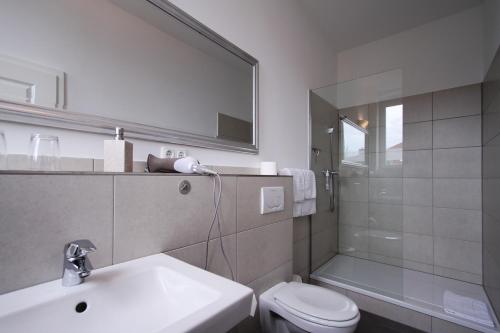 ein Badezimmer mit einem Waschbecken, einem WC und einem Spiegel in der Unterkunft Hotel Galerie in Seelze