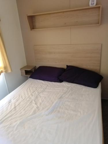 une chambre avec un lit blanc avec des oreillers bleus dans l'établissement YY20 Martello Beach Holiday Park, à Clacton-on-Sea