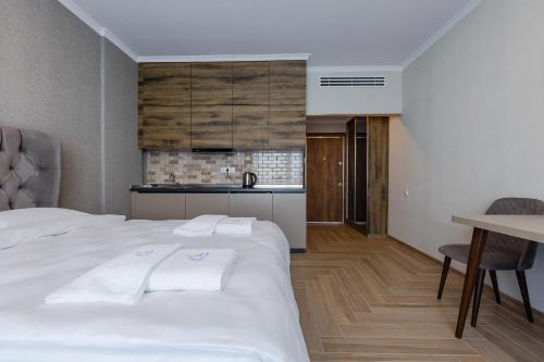 a bedroom with a white bed and a kitchen at Panorama Kvariati in Kvariati