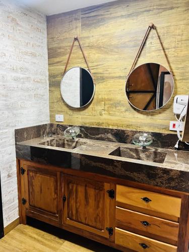 a bathroom with two mirrors above a sink at Chales Cabana Garden in Monte Verde