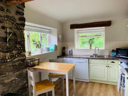 a kitchen with white cabinets and a wooden table at Stable Cottage in Corwen