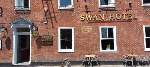 a red brick building with tables and chairs outside at The Swan Hotel in Hythe