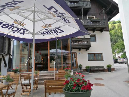 ein Restaurant mit Tischen, Stühlen und einem Sonnenschirm in der Unterkunft Hotel-Pension Hoferhaus in Neukirchen am Großvenediger