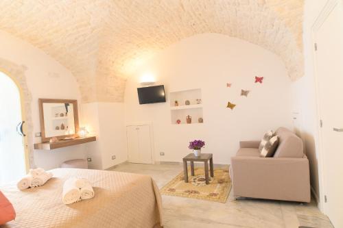 a white bedroom with a bed and a couch at LUXURY ROOM CASSESE in Ceglie Messapica