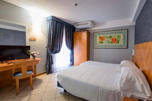 a bedroom with a bed and a desk and a television at Hotel Centrale in Bologna