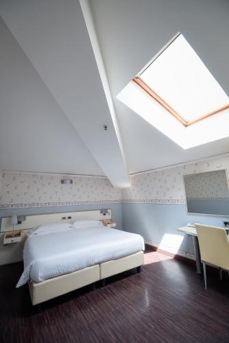 a bedroom with a white bed and a skylight at Hotel Centrale in Bologna
