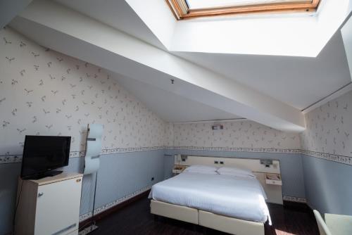 a bedroom with a white bed and a tv at Hotel Centrale in Bologna