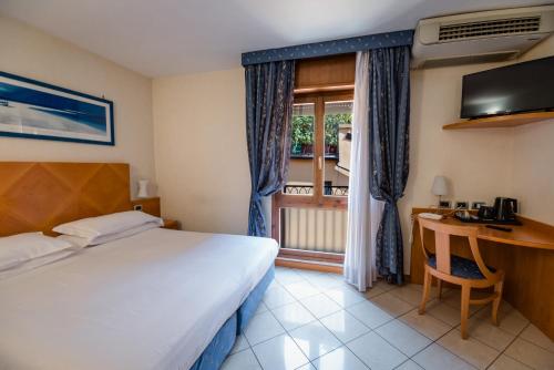 a bedroom with a bed and a desk and a window at Hotel Centrale in Bologna