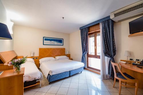 a hotel room with two beds and a desk at Hotel Centrale in Bologna