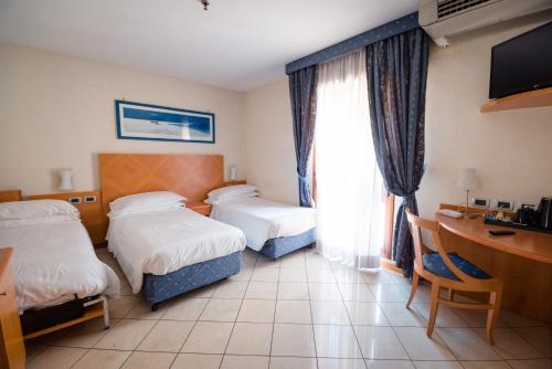 a hotel room with two beds and a desk at Hotel Centrale in Bologna