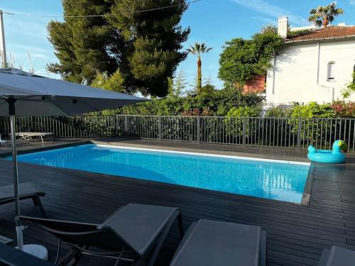 a swimming pool with two chairs and an umbrella at Résidence la Villa Bleue Golfe Juan in Vallauris