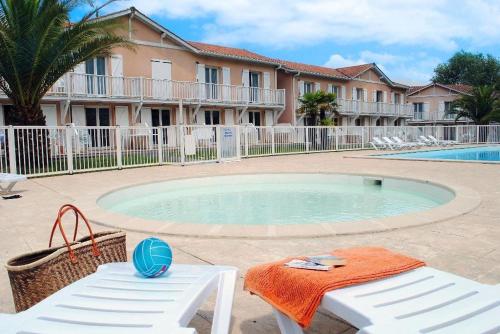 einen Pool mit einem Tisch und Stühlen sowie ein Gebäude in der Unterkunft Petit oasis avec piscine in Anglet