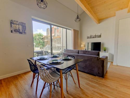 a dining room with a table and chairs and a couch at Coutinho Apartment - Modern Ap in the City Centre with Balcony in Viana do Castelo