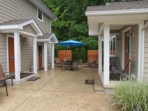 a patio with chairs and an umbrella next to a house at Bodee's Bungalow Adults Only Couples Only Boutique Hotel in Put-in-Bay
