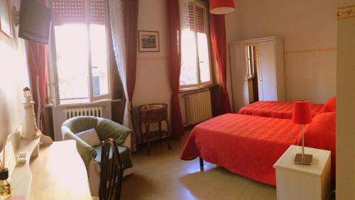 a bedroom with a red bed and a chair and windows at B&B Borgomarino in Pescara