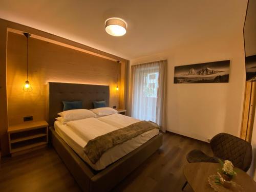 a bedroom with a large bed and a table at Hotel Garni Walter in Ortisei