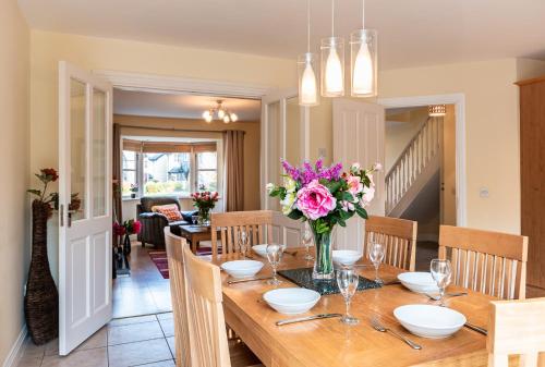 a dining room with a table with a vase of flowers at Foleys Ardmullen Townhouses in Kenmare