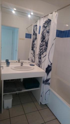 baño con lavabo y cortina de ducha en Soulac-Sur-Mer avec Piscine, en Soulac-sur-Mer