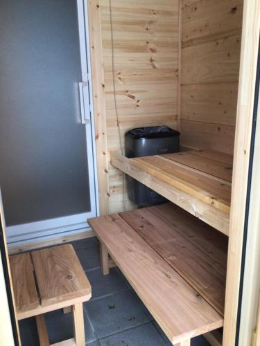 a wooden sauna with two benches and a trash can at Log Cottage 白馬KIITOS in Hakuba