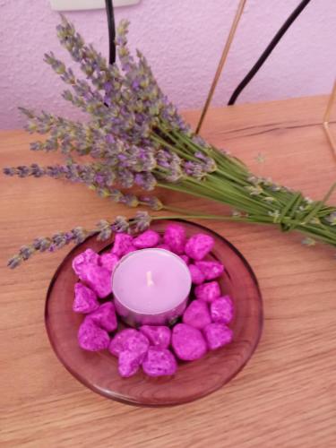 un plato con una vela y flores en una mesa en Apartman Lavanda, en Trebinje