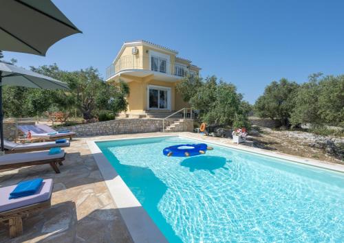 a villa with a swimming pool in front of a house at Villa Agnanti in Vlachopoulátika