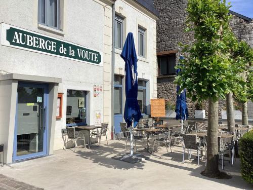 an outdoor cafe with tables and chairs and blue umbrellas at AUBERGE DE LA VOUTE in Chooz