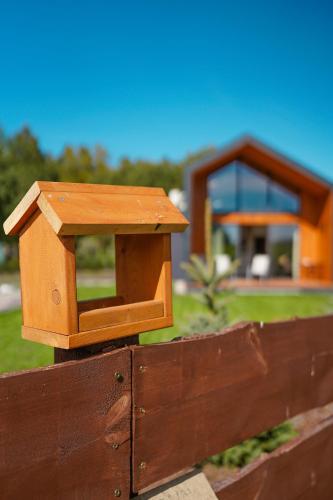 a wooden fence with a bird house on it at Szumiące Trawy - Bory Tucholskie in Tleń