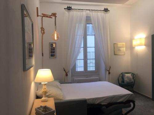 - une chambre avec un lit doté d'une fenêtre et d'une lampe dans l'établissement Charmant Studio avec Mezzanine, Climatisé, au Cœur de Menton, Proche Plages et Commerces - FR-1-196-300, à Menton