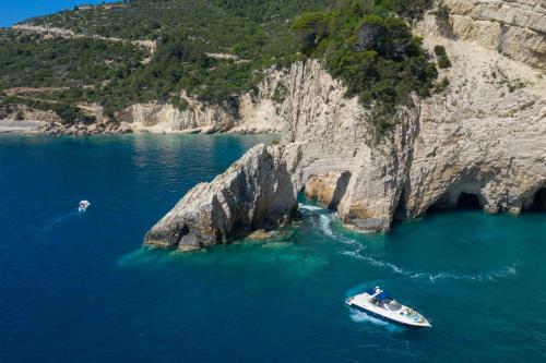 a boat in the water next to a cliff at Daily Cruises Private Yachts in Zakynthos Town