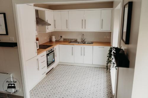uma pequena cozinha com armários brancos e um lavatório em Stylish Belfast City Centre 2 Bedroom Apt Free Parking em Belfast