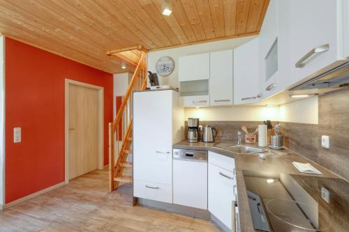 a kitchen with white cabinets and a red wall at La Mer in Altefähr