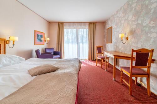 a hotel room with a bed and a desk and chairs at Hotel Heiderhof in Obersteinebach
