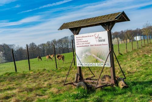 a sign in a field with horses in the background at Hotel Heiderhof in Obersteinebach