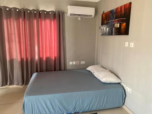 ein kleines Bett in einem Zimmer mit einem roten Vorhang in der Unterkunft Newly Built 2 bedroom En-suite Apt. in Accra