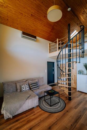 a living room with a couch and a spiral staircase at Szumiące Trawy - Bory Tucholskie in Tleń