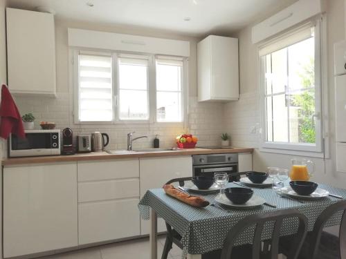 a white kitchen with a table and a table and chairs at Gîte de l'Alisier - Rambouillet - in Rambouillet