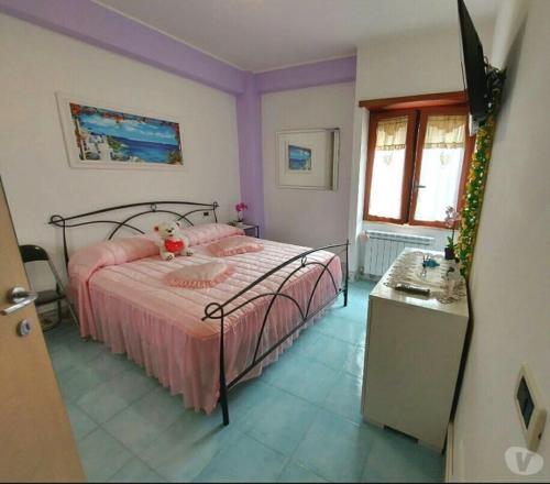 una camera da letto con un letto con lenzuola rosa e una finestra di Graziosa casa vacanza vicino al mare a Sperlonga centro! a Sperlonga