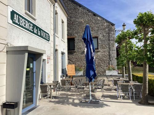 a patio with tables and chairs and a blue umbrella at AUBERGE DE LA VOUTE in Chooz