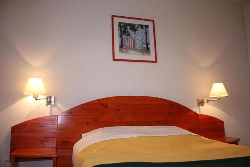 sypialnia z drewnianym łóżkiem z 2 lampami w obiekcie Soulac-Sur-Mer avec Piscine w mieście Soulac-sur-Mer