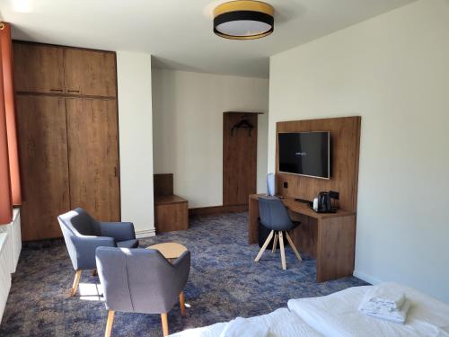Habitación de hotel con cama, sillas y TV. en Pension zum Kleistpark en Frankfurt/Oder