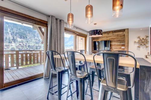 une salle à manger avec une table et des chaises et un balcon dans l'établissement Frênes Blancs 105, à Morzine