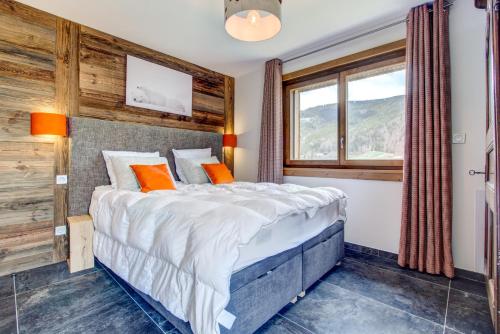 une chambre avec un grand lit avec des oreillers orange dans l'établissement Frênes Blancs 105, à Morzine