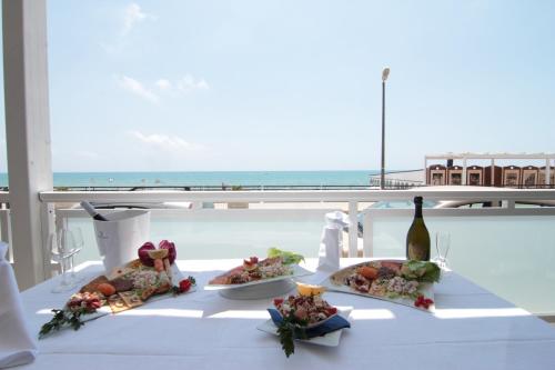 einen Tisch mit 2 Tellern Essen und einer Flasche Wein in der Unterkunft Hotel Miramare in Marina di Ragusa